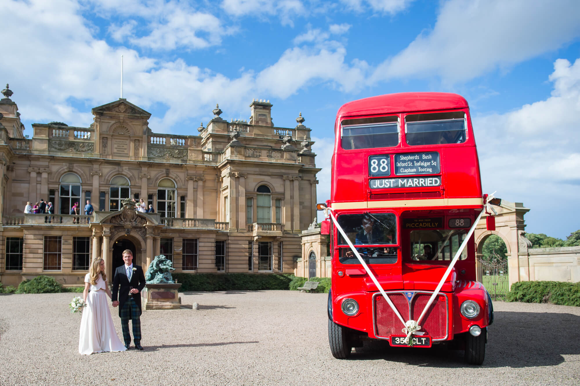 A bride and groom outside gosford house with a vintage red bus by especially amy wedding photography